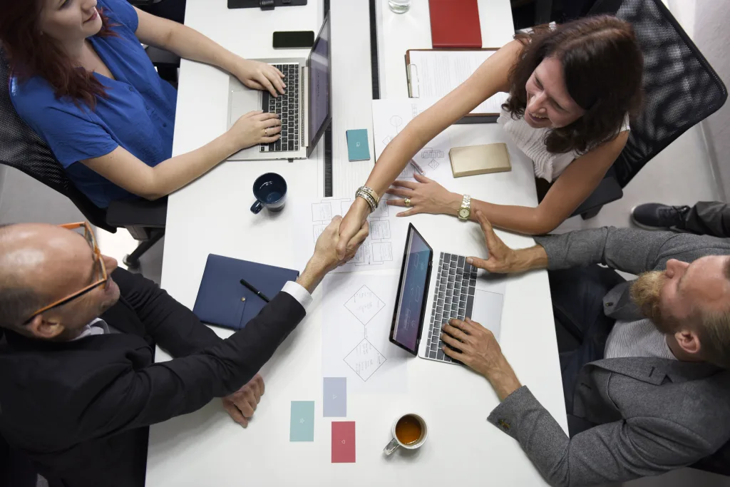 4 team members working together on a project and 2 shaking hands